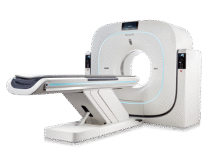 A white Neusoft NeuViz 128 CT scanner with its patient table extended, illuminated by blue light.