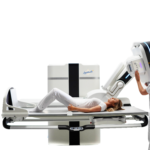 Patient lying on an mri scanner bed as a clinician operates the controls beside the machine.