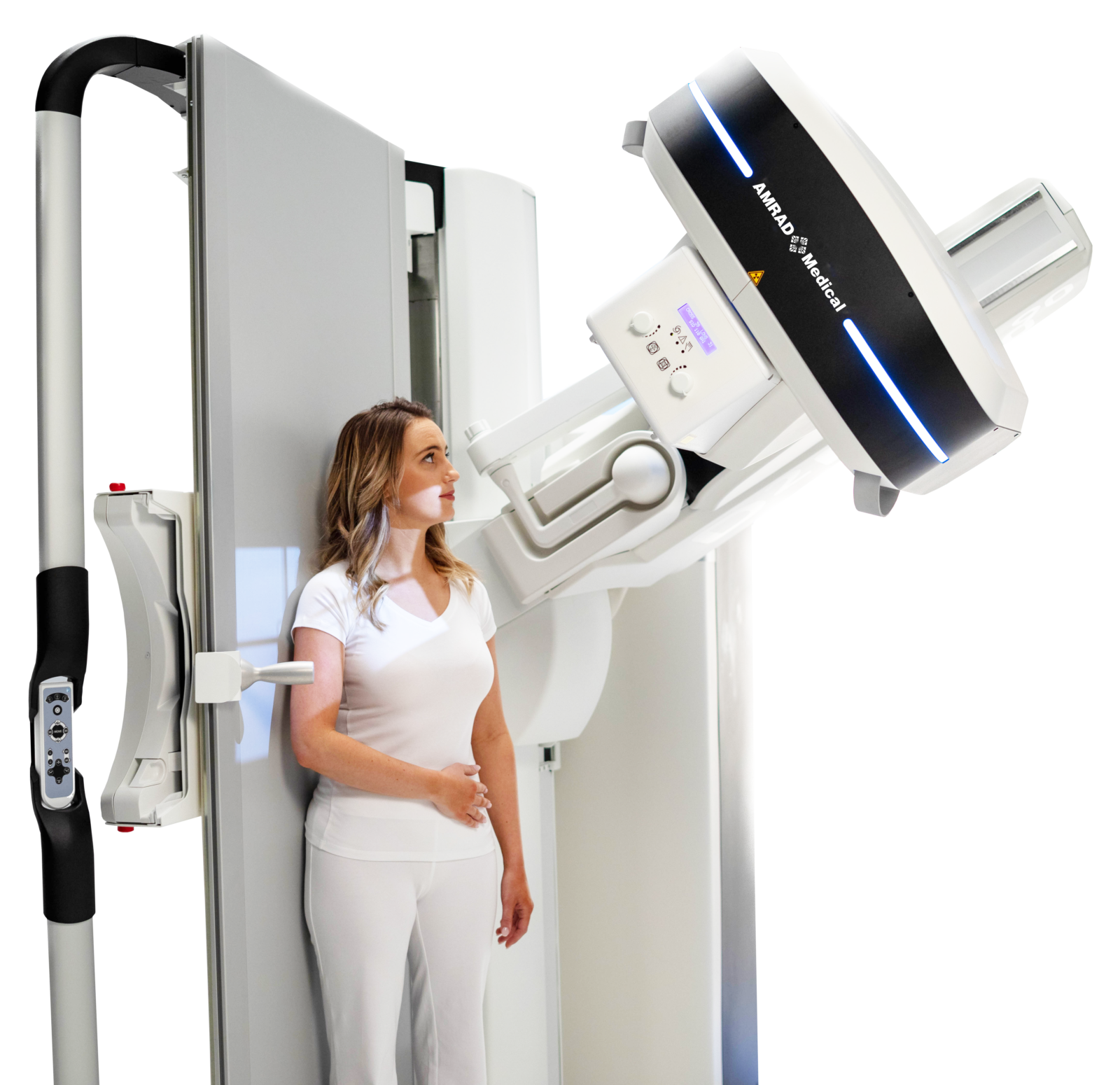 Woman in white standing beside an mri scanner, looking at the machine near the bed. (informative)