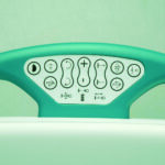 Close-up of a curved teal control panel with multiple circular buttons and icons for adjusting position on a chair or bed.