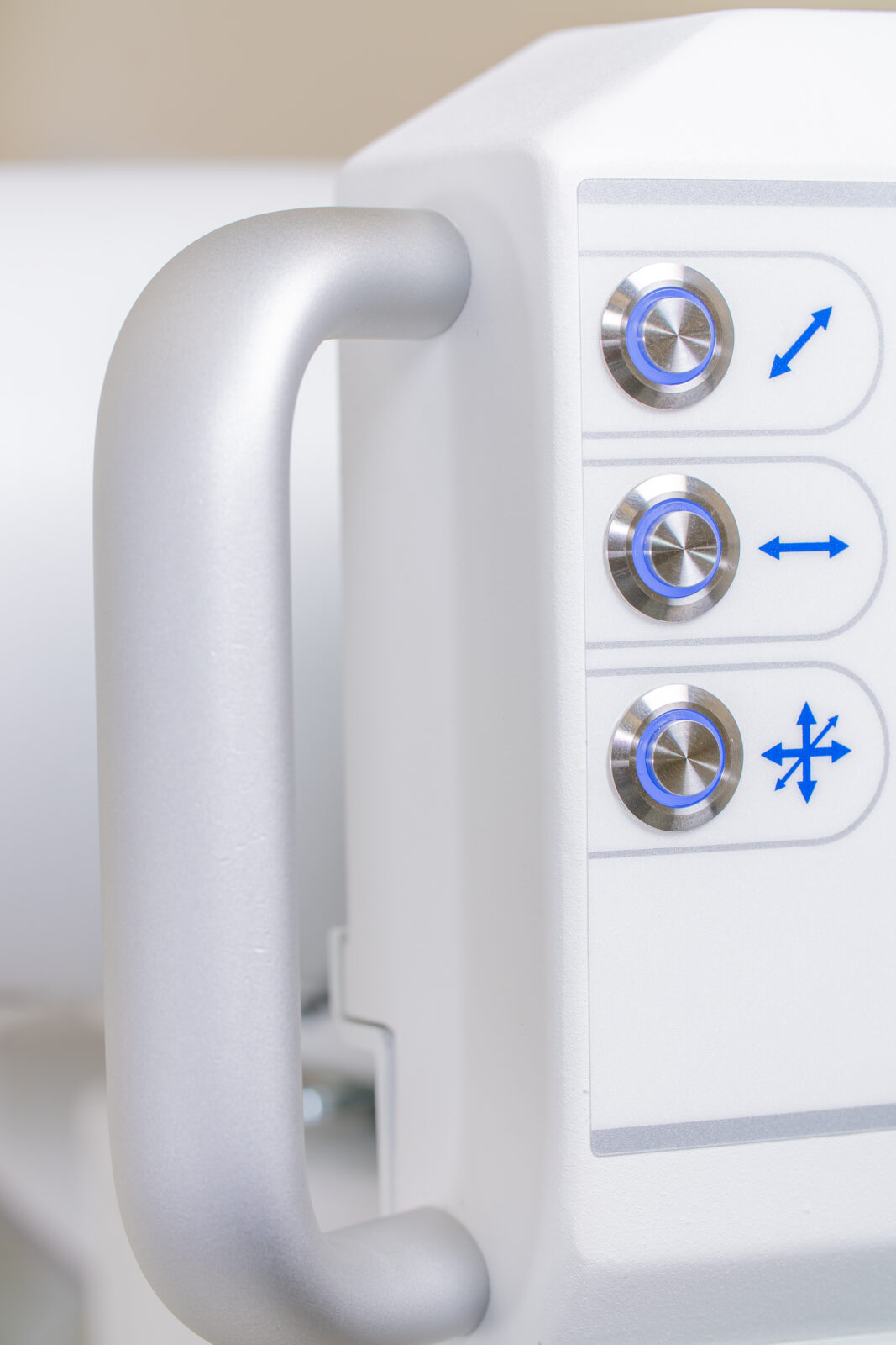 Close-up of a white medical device control panel with blue-lit circular knobs and directional arrows on the right side of the unit.