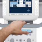 Person holding a handle while operating a medical device with a touchscreen control panel, seen from above