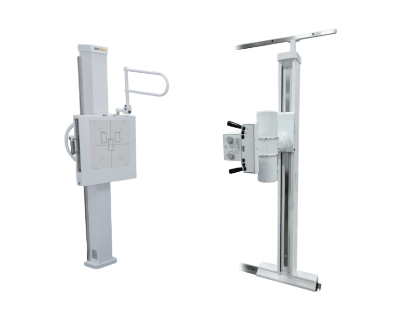Two upright radiography stands with vertical columns and attached control panels, shown side by side. One has a wall-mounted console and a curved support arm, the other features a vertical rail with a mounted control unit.