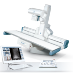 Medical imaging system with a patient table and an x-ray gantry, plus a workstation monitor displaying diagnostic images.