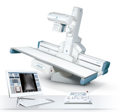Medical imaging system with a patient table and an x-ray gantry, plus a workstation monitor displaying diagnostic images.