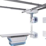 Ceiling-mounted radiography system with a movable gantry over an exam table and wall-mounted control panels.