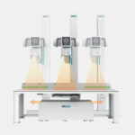 Three-arm drgem dental imaging system on a stand, projecting orange light cones onto a surface beneath for scanning.