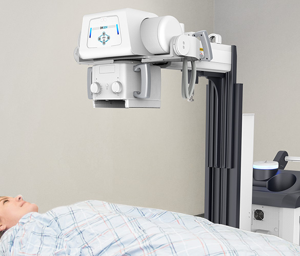 Medical imaging device (x-ray/fluoroscopy) positioned over a patient lying on an examination bed for a radiographic exam