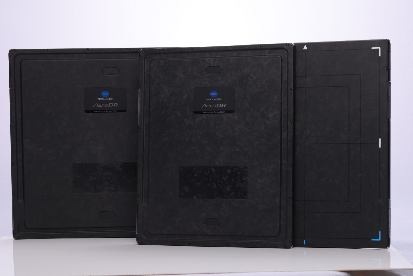 Back view of three black aerodr imaging panels with konica minolta branding on a white surface/wall.