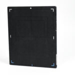 Tall black rectangular box standing on a white surface with white corner markings and blue accents at the bottom edge against a white background.