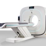 Ct scanner with round bore and conveyor-style patient table in a clinical setting, glowing blue light accents nearby