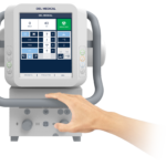 Ventilator control panel with a touchscreen display and a hand adjusting a dial and buttons (medical device)