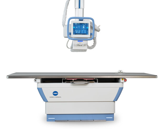 Medical x-ray radiography table with an overhead display monitor mounted above for diagnostic imaging.