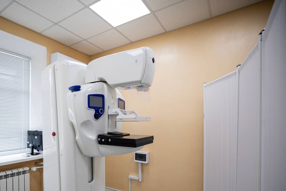 Medical imaging room with a large white radiology machine and patient table in beige walls