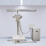 Medical x-ray imaging machine mounted on a vertical stand in a stark, clean radiology room.