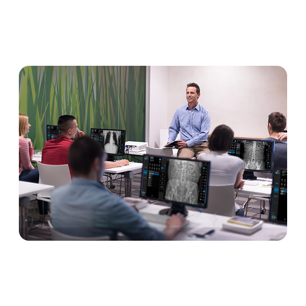 Instructor presenting to clinicians in a radiology training room, with brain mri images on monitors.