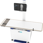 Medical imaging device with a tablet-style screen showing a spine x-ray on a stand behind a white unit (drgem).