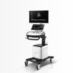 Mobile ultrasound cart with dual screens and a probe tray, used for point-of-care imaging in clinics/wards.