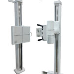 Two vertical radiography stands with a control panel, used for taking x-ray images in a medical setting.