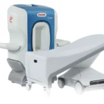 Blue-and-white medical imaging scanner with a wheeled patient table extended for a scan, likely mri/ct equipment used to image patients' bodies