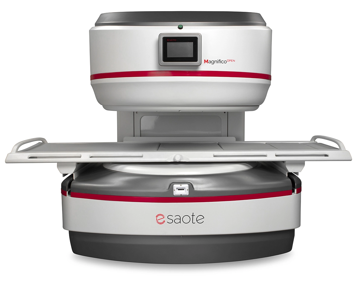 Open mri scanner (magnifico open by saote) with the patient table extended, ready for imaging in a white-gray unit with red accent stripe.