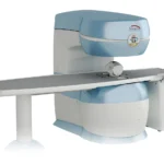 Medical mri scanner with a wide patient table, light blue and white housing, viewed from the side