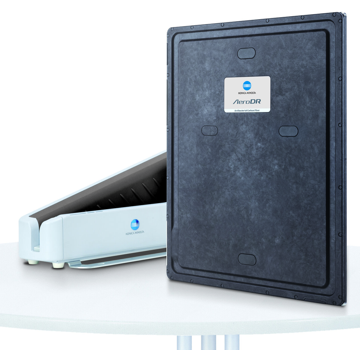 Blue konica minolta aerodr flat-panel detector standing upright beside its light-blue reader on a white table.