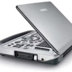 Open silver portable scanner/fax with a raised lid showing the illuminated control panel and front card slot, ready for scanning or copying lines of text.